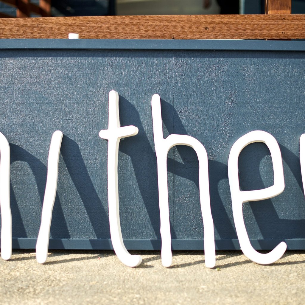 All the letters from the Hither Coffee + Goods sign leaning against a wall